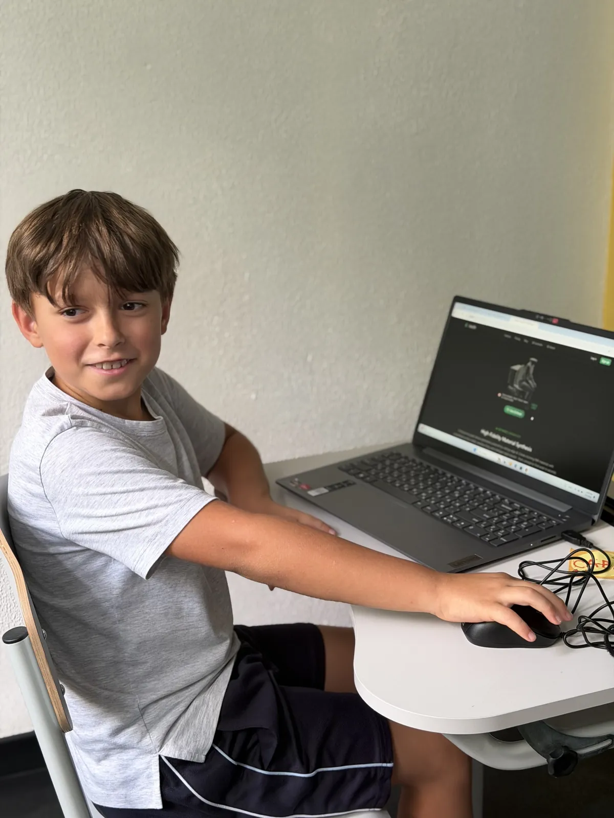 Un băiat zâmbește la laptop, în timpul lecției